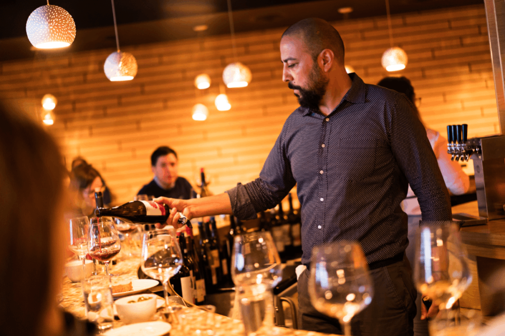 Flight Owner + Sommelier Kabir Amir pours wine at the bar.