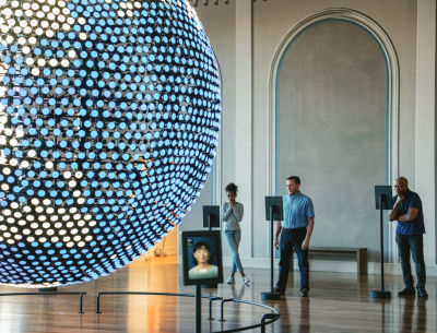 A large disco ball in the foreground. People singing in the background at Planet Word, a local spot in D.C.