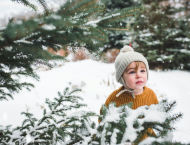 A child stands among snow-covered trees.