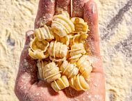 A hand holds fresh pasta.