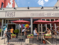 People sit outside under red umbrellas, outside of Tryst coffeehouse.