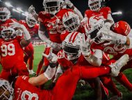 Football players wearing red look at the camera.