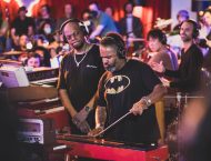 People in Batman t-shirts stand next to a keyboard.