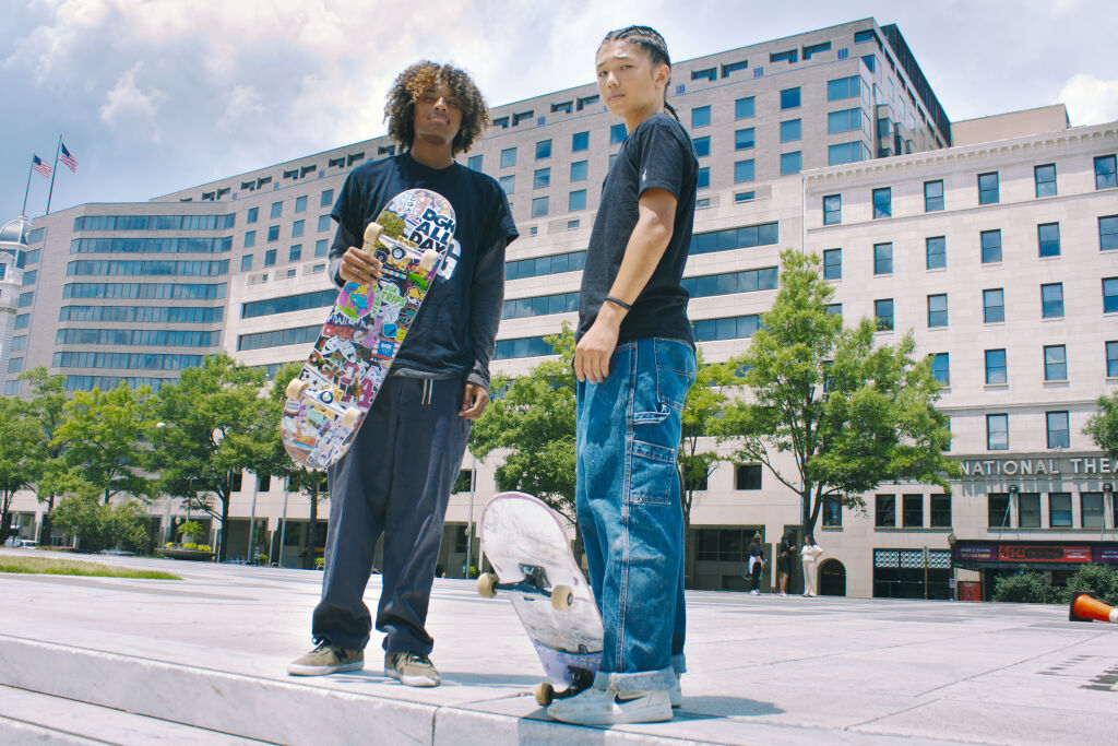 Two skaters, Eric and Gabe, stand outside at Freedom Plaza with their skateboards.