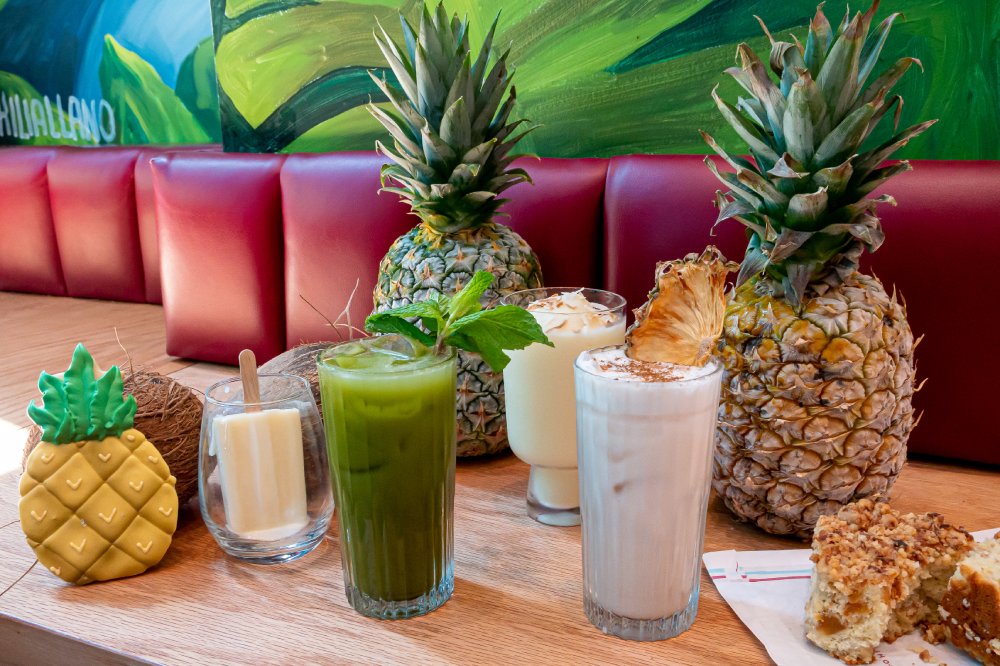 Frozen cocktails sit on a table next to pineapples and bites at Colada Shop.