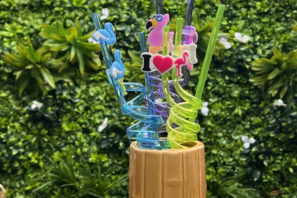 Drink with many straws with a background of greenery.